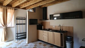 Een keuken met houten kastjes, een zwart aanrecht en een raam met beige gordijnen.