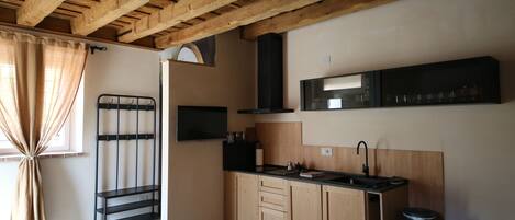 A kitchen with wooden cabinets, a black countertop, and a window with beige curtains.