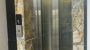 Een lift met een marmeren wand en een bedieningspaneel met een euro symbool.