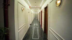 Een hotelgang met een gepoetste vloer, deuren aan beide zijden en een plafondlamp.