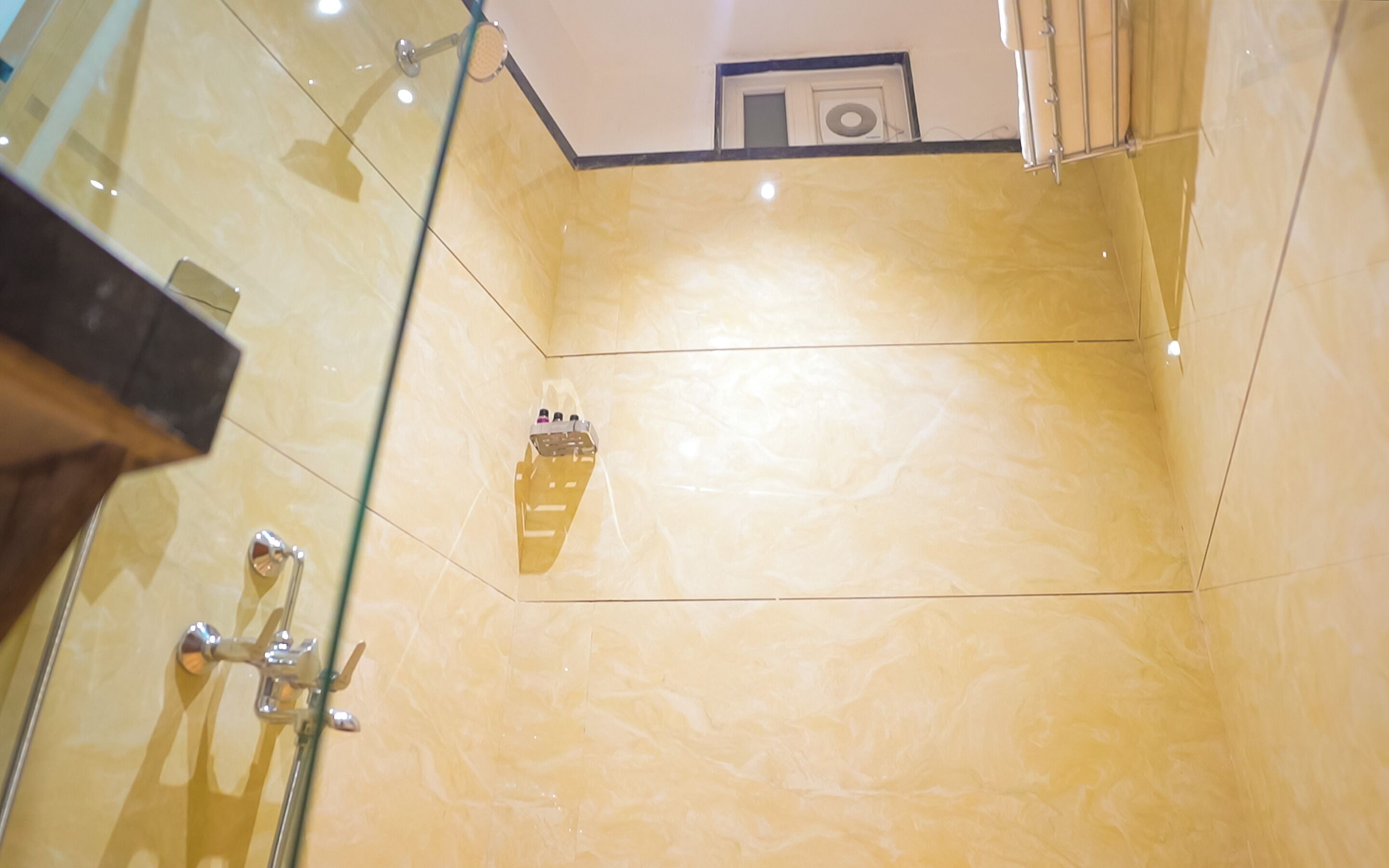 A bathroom with a glass shower enclosure, a marble wall, and a mounted towel rack.
