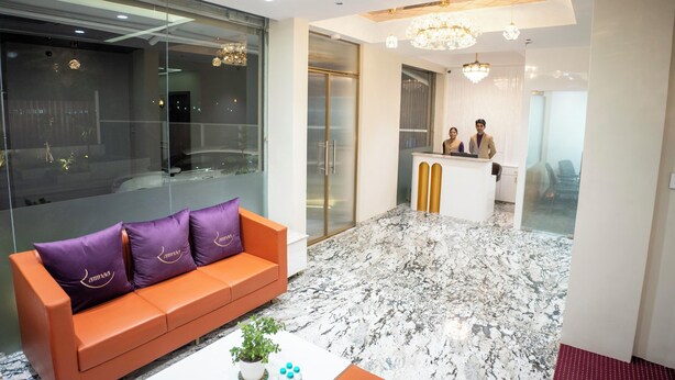 Een moderne lobby met een receptiebalie, een zithoek met een bank en een bijzettafeltje, en een marmeren vloer.