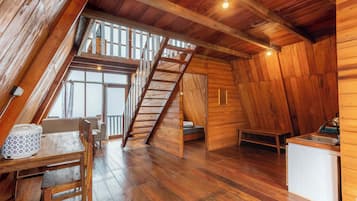 Un interno in legno con una zona notte soppalcata, un'area pranzo e un angolo cottura.