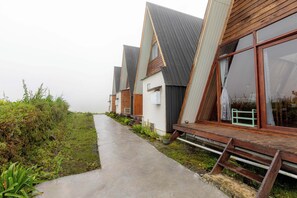 A row of modern, wooden-roofed buildings with large windows, a concrete pathway, and greenery. - Padangsari Cabin 2 (Kejajar)