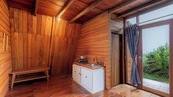 A wooden cabin interior with a bench, a sink, and a window with curtains.