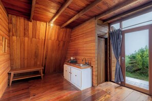 A wooden cabin interior with a bench, a sink, and a window with curtains. - Padangsari Cabin 2 (Kejajar)