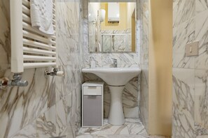 A bathroom with a marble sink, a mirror, and a towel rack. - Homiday – Incanto is a bright and cozy apartment located on Via Pietrasantina, just a few minutes’ walk from the Leaning Tower of Pisa and Piazza dei Miracoli.Situated in a convenient and quiet area, it allows you to experience the city stress-free.  (Pisa)