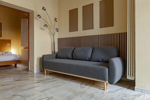 A modern living room with a grey sofa, a wooden floor, and a radiator. - Homiday – Incanto is a bright and cozy apartment located on Via Pietrasantina, just a few minutes’ walk from the Leaning Tower of Pisa and Piazza dei Miracoli.Situated in a convenient and quiet area, it allows you to experience the city stress-free.  (Pisa)