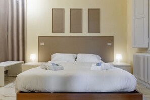 A neatly arranged hotel room with a large bed, two bedside tables with lamps, a wooden headboard, and three framed pictures on the wall. - Homiday – Incanto is a bright and cozy apartment located on Via Pietrasantina, just a few minutes’ walk from the Leaning Tower of Pisa and Piazza dei Miracoli.Situated in a convenient and quiet area, it allows you to experience the city stress-free.  (Pisa)