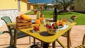 Una mesa al aire libre con alimentos para el desayuno, una botella y un vaso de jugo de naranja.