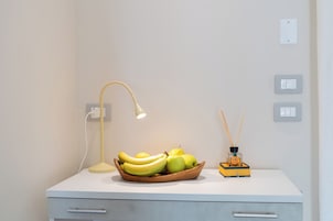 A desk with a lamp, a bowl of fruit, and a diffuser.