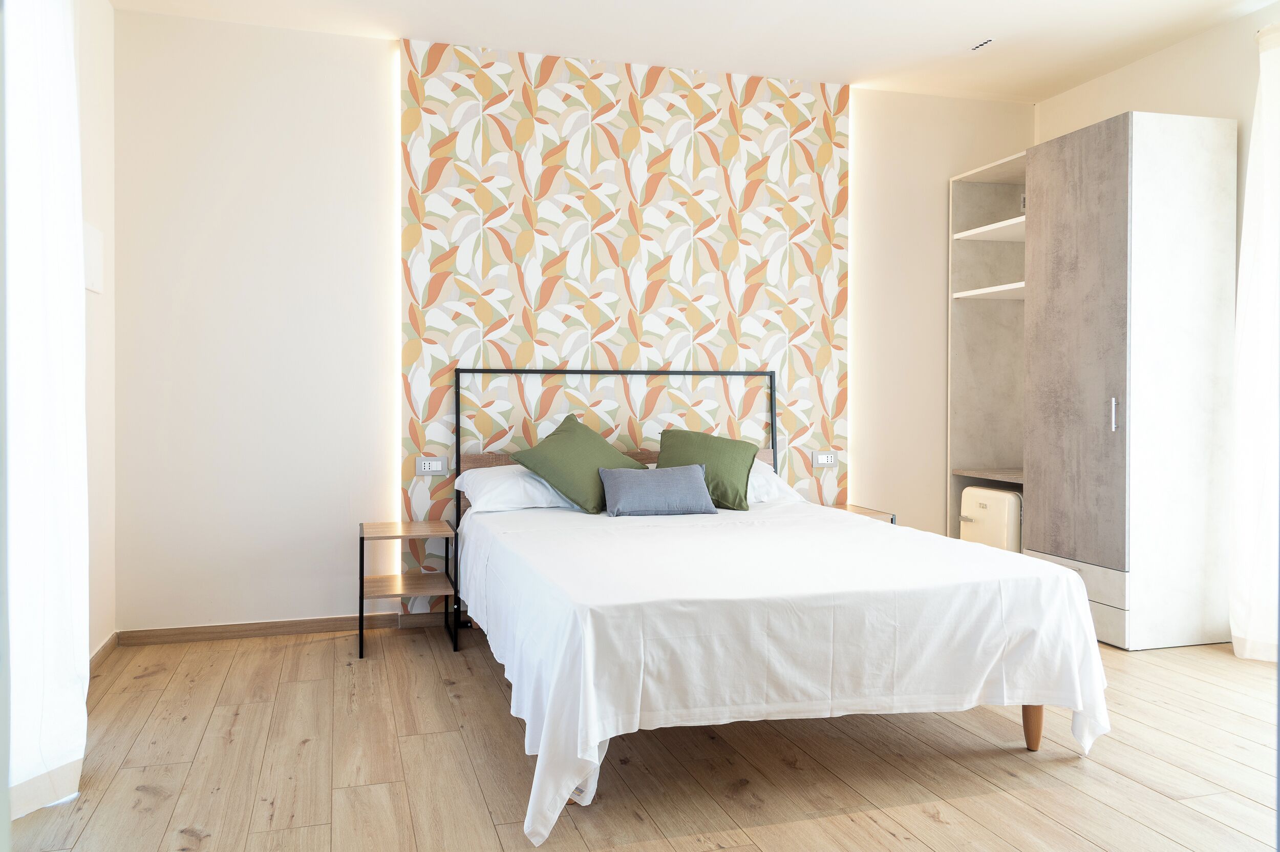 Une chambre à coucher avec un lit, une armoire et un papier peint à motifs.