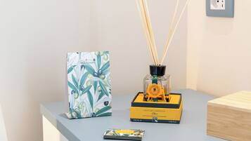 Une petite table sur laquelle se trouvent un diffuseur de parfum à bâtonnets, un tableau encadré et une petite boîte.