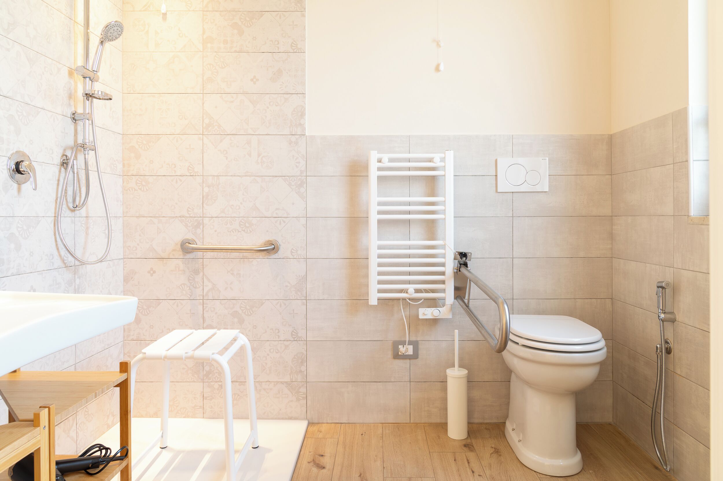 A modern bathroom with a shower, toilet, and a small white stool.