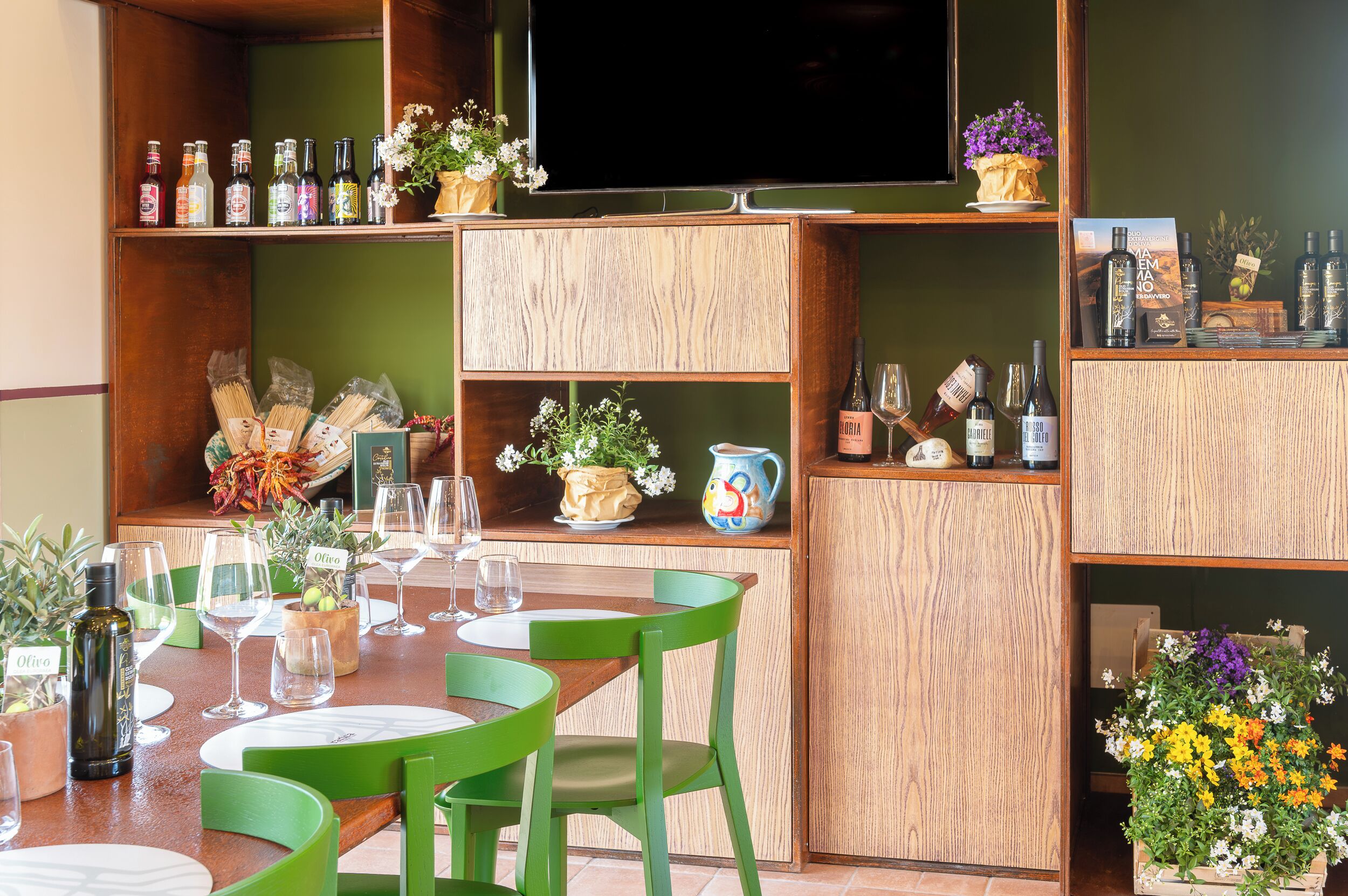 A dining area with a wooden table, green chairs, and a TV mounted on the wall.