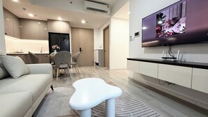 Un salon moderne avec un canapé, une table basse blanche et un téléviseur à écran plat fixé au mur.