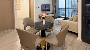Un salon moderne avec une table ronde, deux chaises, un canapé et un téléviseur.