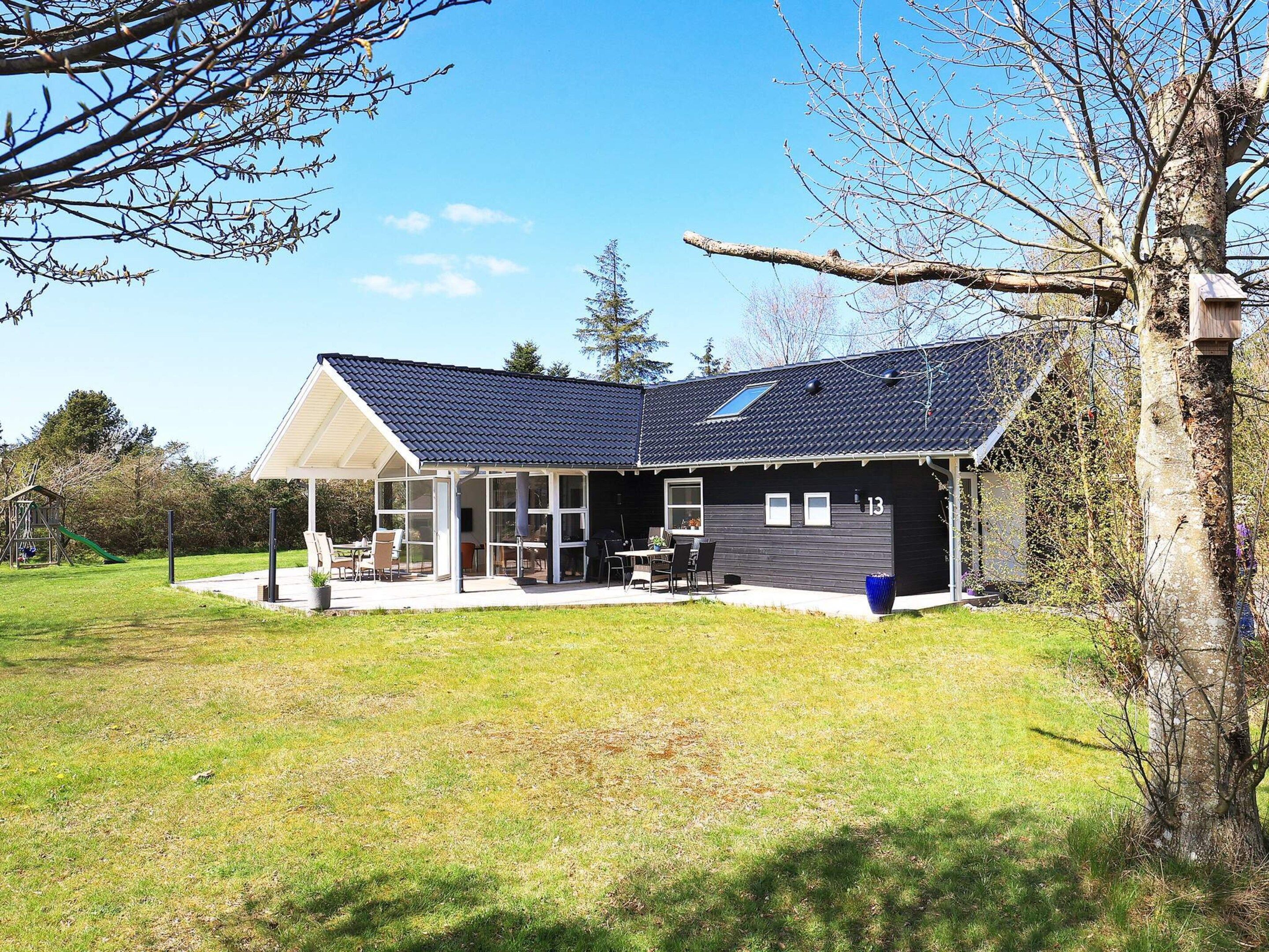 A modern house with a covered patio, a play area, and a number 13 on the side.