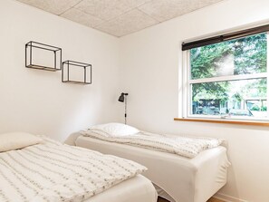 Ein Schlafzimmer mit zwei Betten, einem Fenster mit Blick auf Grünflächen und zwei Wandleuchten.