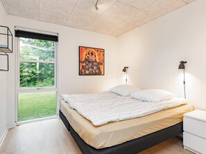 A bedroom with a bed, two bedside lamps, a window, and a painting on the wall. - 5 Star Holiday Home in Hals (Hals)