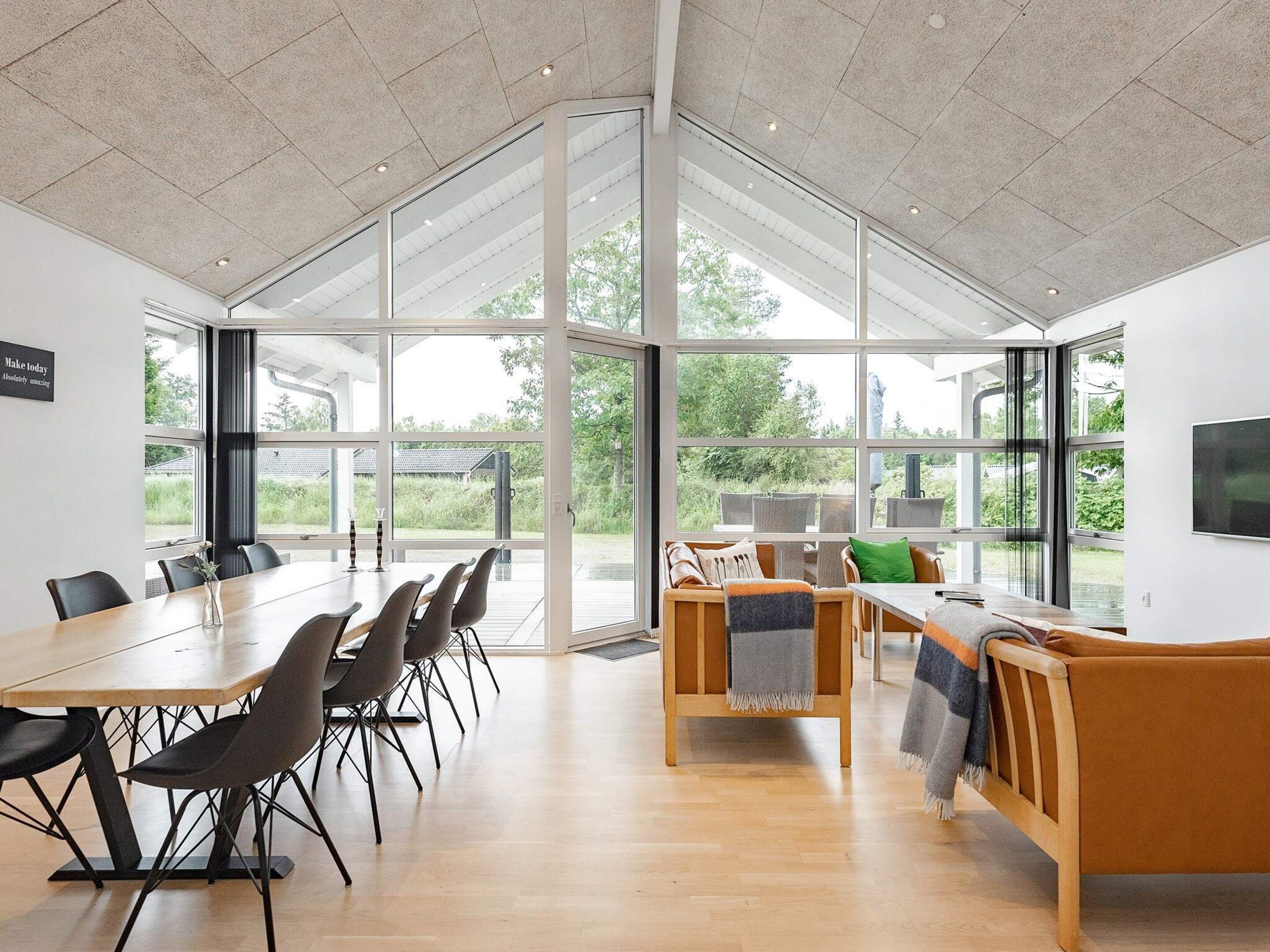 A spacious room with a large table and chairs, a sofa, and a television.
