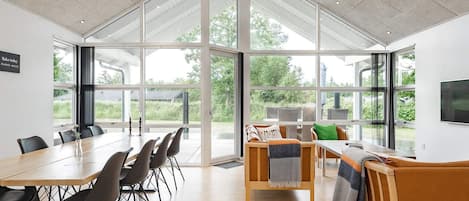 A spacious room with a large table and chairs, a sofa, and a television.