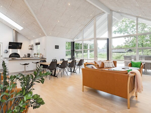 A modern kitchen with a dining area, large windows, and a cozy seating area. - 5 Star Holiday Home in Hals (Hals)
