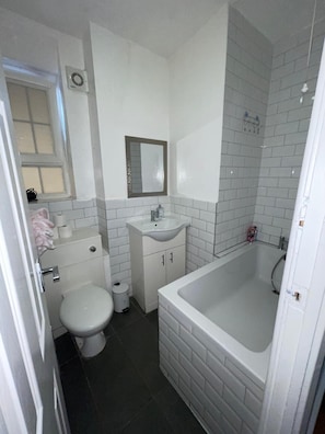 A compact bathroom with a toilet, sink, and bathtub. - Charming 2 Bedroom Apartment in Central London (London)