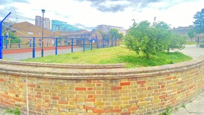 A brick wall, a grassy area, and a blue fence. - Luxurious 5 Bedroom Home in Prime London Location (London)