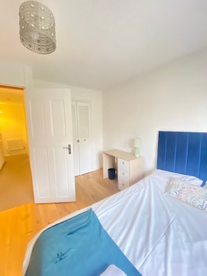 A bedroom with a bed, a desk, a wardrobe, and a door leading to another room. - Luxurious 5 Bedroom Home in Prime London Location (London)