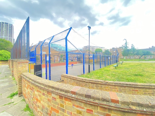 A sports facility with a fenced area, a brick wall, and a pathway. - Luxurious 5 Bedroom Home in Prime London Location (London)