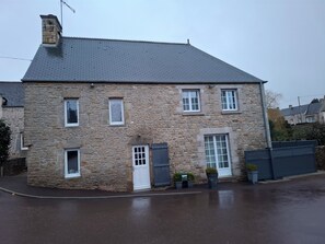 A stone building with a sloped roof, multiple windows, and a door. - Stone house 170m³ Pleasant. 2 to 10 people .2 days to 1 or 2 weeks (Tocqueville)