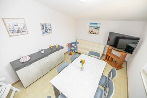 Eine kompakte Küche mit Esstisch, Stühlen, einer Couch und einem Fernseher.
