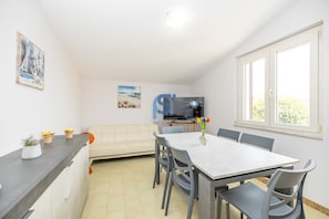 Ein kompakter Wohnbereich mit Küchenzeile, Essplatz, Sofa und Fernseher.