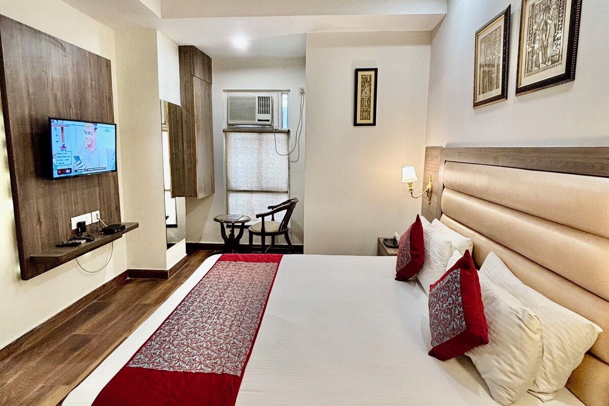 A hotel room with a large bed, a television, a desk, and a chair.