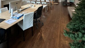 A spacious conference room with a long table, white chairs, and a Christmas tree.