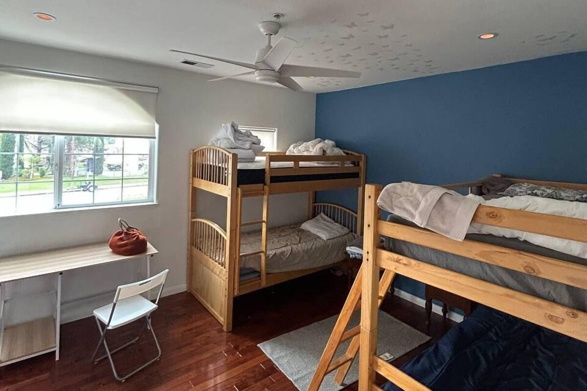 Une chambre de dortoir avec des lits superposés, un bureau, une chaise et une fenêtre donnant sur un paysage agréable.