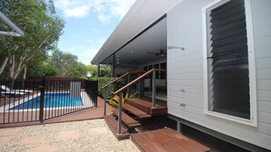 Un espace piscine doté d’une terrasse en bois, d’une piscine clôturée et d’un coin salon extérieur abrité.