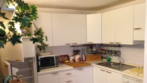 Une cuisine de taille réduite, avec des meubles blancs, un four à micro-ondes, un évier et un lave-vaisselle.