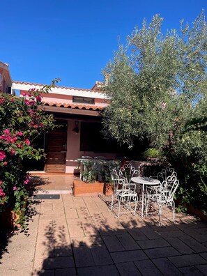 Une terrasse avec des meubles d’extérieur, une porte et un jardin.