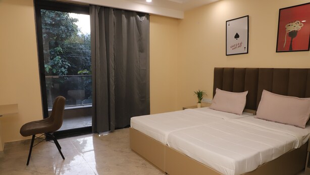 Un dormitorio con cama, una silla, un ventanal con cortinas y una planta.
