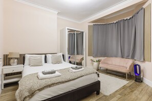 A bedroom with a bed, bedside table, nightstand, and a chair. - 2BR in Kensington, 2 min Earls Court tube (London)