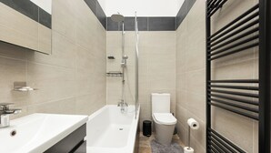 Moderni kylpyhuone, jossa on kylpyamme, wc ja suihku.