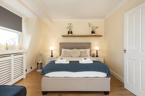 A bedroom with a bed, bedside tables, lamps, a window, and a door. - Zew! Top Floor 1BR w/Balc, Earl’s Court, 2min Tube (Greater London)