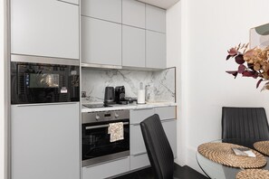 A modern kitchen with a built-in oven, a coffee maker, and a marble countertop. - Lovely 2BR flat in Kensington, 2 minutes tube (London)