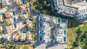 Eine Luftaufnahme eines Resorts mit mehreren Schwimmbecken, die in einem rasterartigen Muster angeordnet sind, umgeben von üppiger Vegetation und einigen Gebäuden.