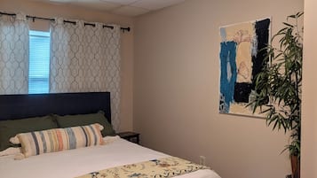 Une chambre à coucher avec un lit, une table de chevet, un tableau accroché au mur et une plante en pot.