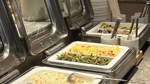 Ein Buffet mit mehreren Speiseauslagen, darunter Reis, Gemüse und Salat.