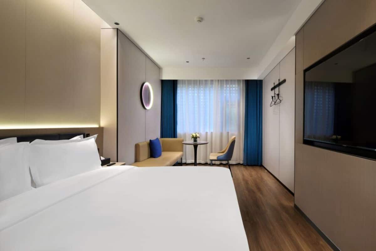 Ein modernes Hotelzimmer mit einem großen Bett, einer Sitzecke, einem kleinen Tisch und einem Fernseher.