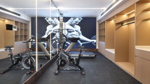 Ein Fitnessstudio mit Trainingsgeräten, einem großen Spiegel und einer Wand mit einer Darstellung einer muskulösen Person.